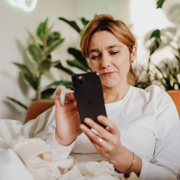 Kvinna använder smartphone i soffan hemma